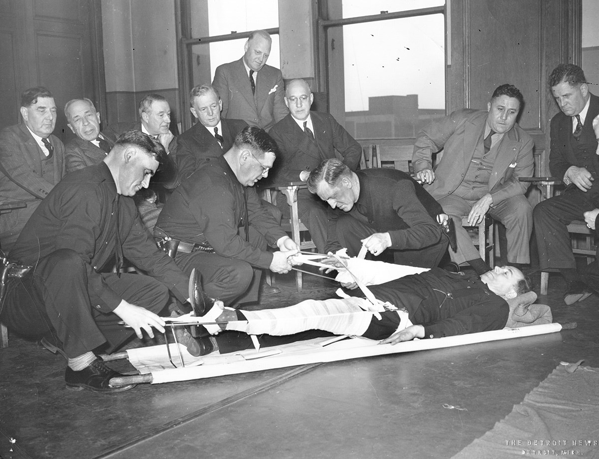 A demonstration of stabilizing a broken leg in a 1922-era medical classroom. 